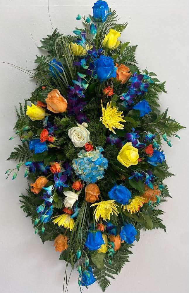 Corona floral colorida con rosas azules, amarillas, naranjas y flores frescas variadas.