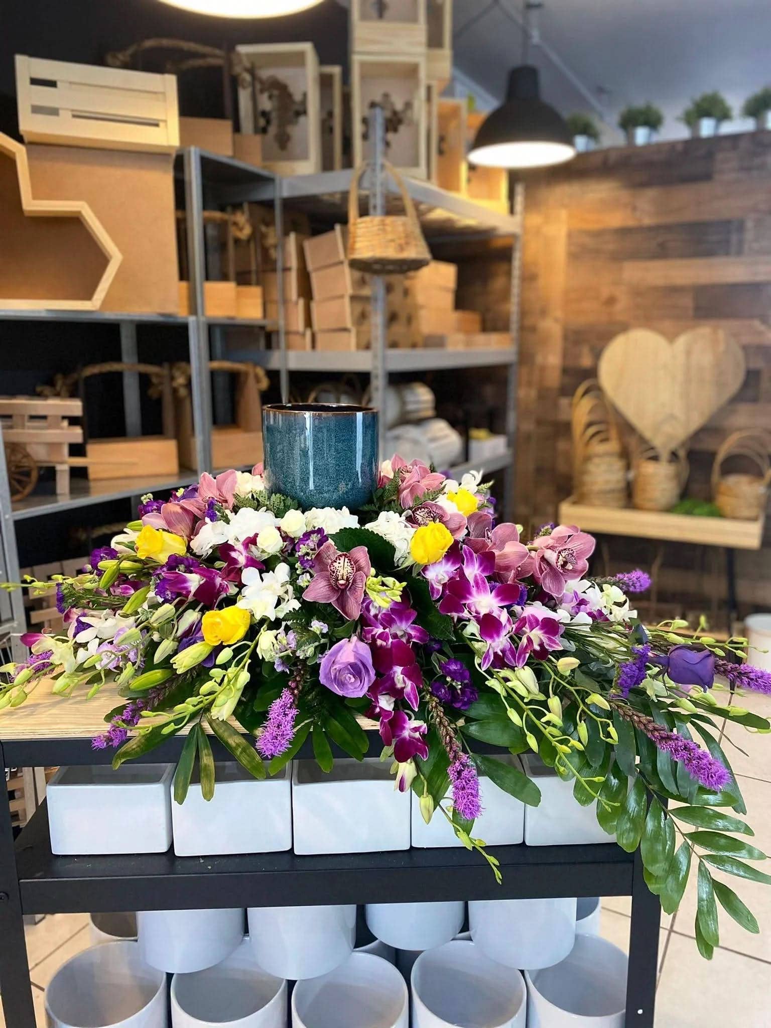 Porta cenizas azul decorado con arreglo floral de orquídeas y rosas en tonos morados y amarillos